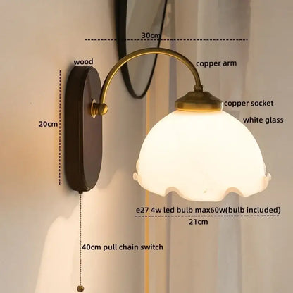 Antique brass floral frosted glass led wall light with dark wood backplate and curved copper arm for bedroom sconce