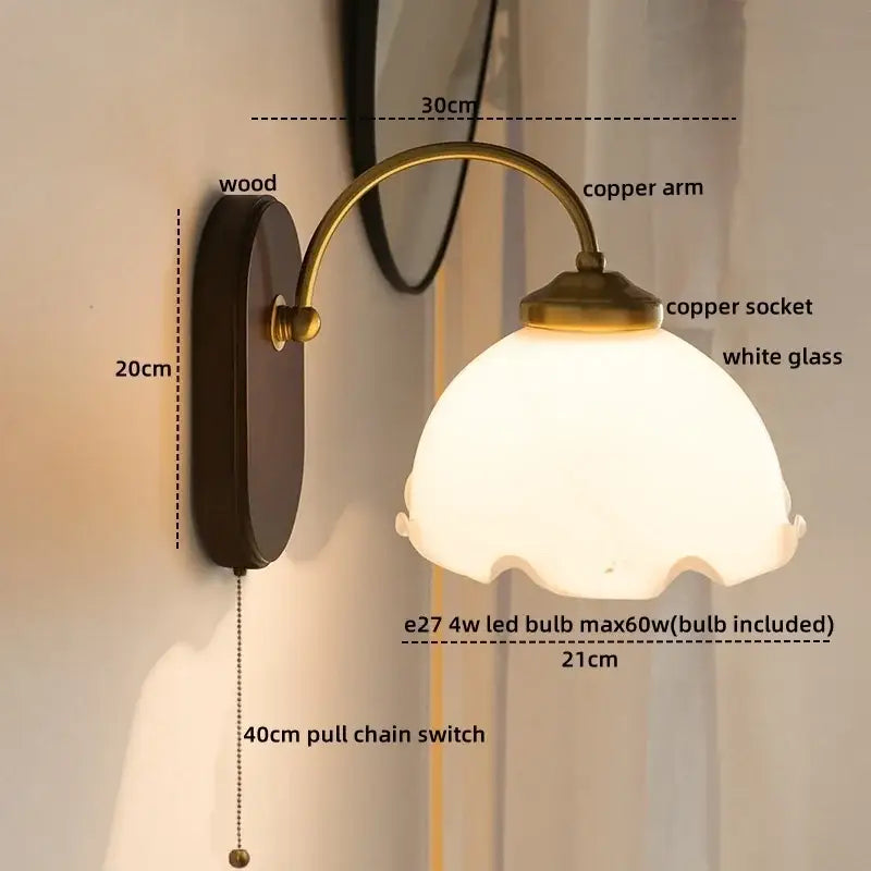 Antique brass floral frosted glass led wall light with dark wood backplate and curved copper arm for bedroom sconce