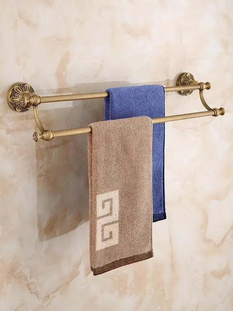 Antique brass floral bathroom hardware set double tier towel rack with ornate ends holding blue and beige towels