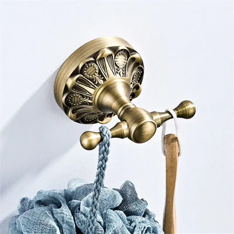 Antique brass double towel hook with ornate scalloped design and two spherical ends from brass bathroom hardware set