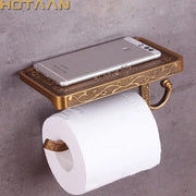 Antique brass toilet paper holder with ornate floral engraving and matching phone rack for bathroom use