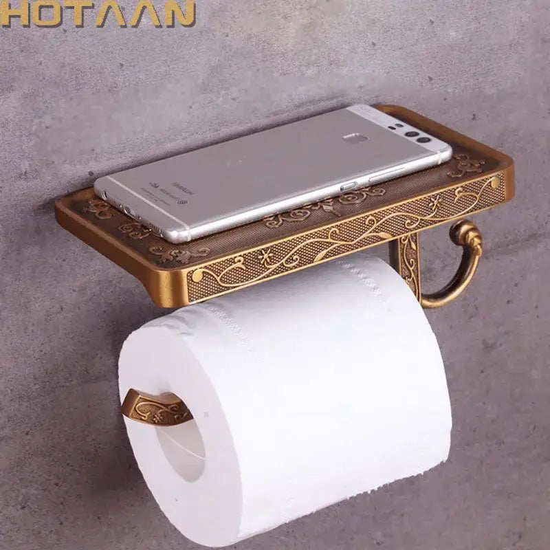 Antique brass toilet paper holder with ornate floral engraving and matching phone rack for bathroom use