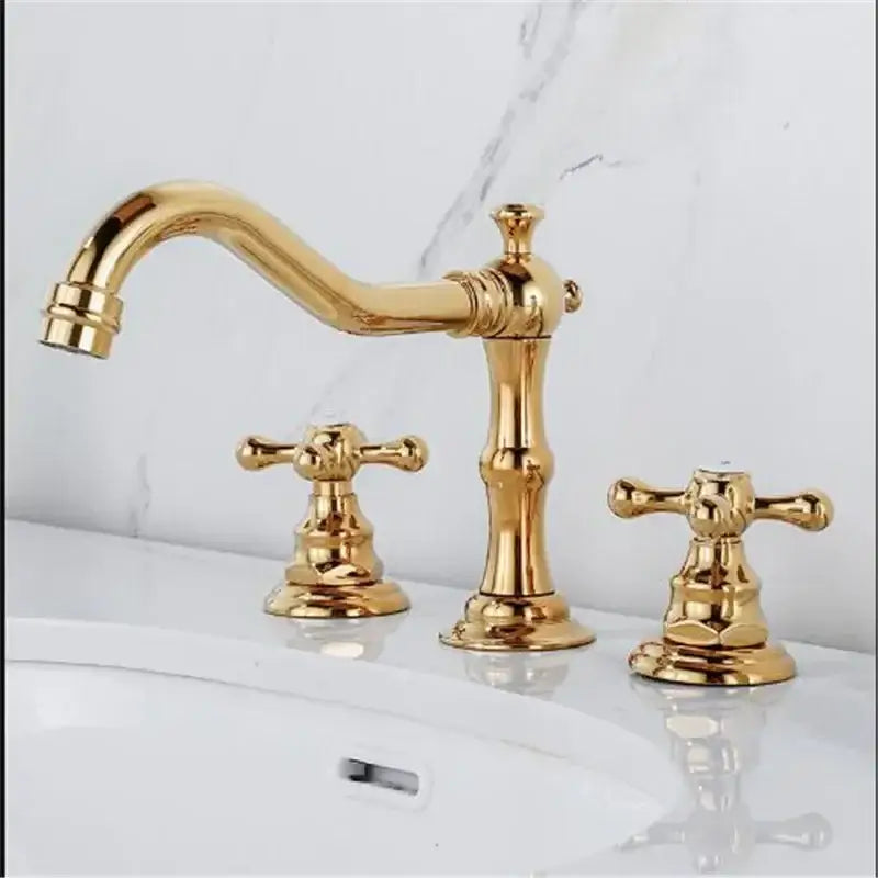 Antique brass gold finish bathroom sink faucet with three ornate cross handles and a curved spout