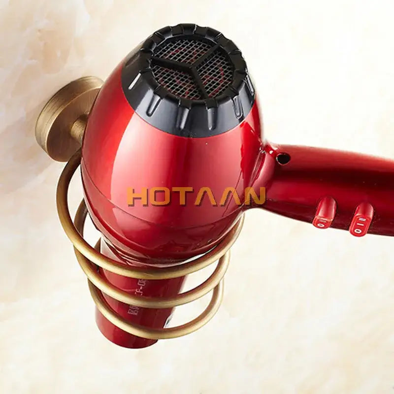 Antique brass hair dryer holder rack with triple loop design holding a red hair dryer with black mesh grille and gold stand
