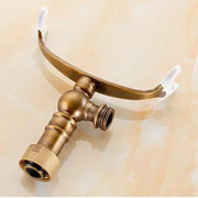 Antique brass hand shower holder with curved spout and two white plastic mounting clips for bathroom use