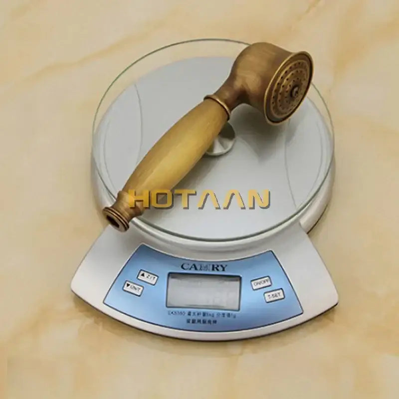 Antique brass hand shower set with wood handle resting on a digital scale for bathroom use