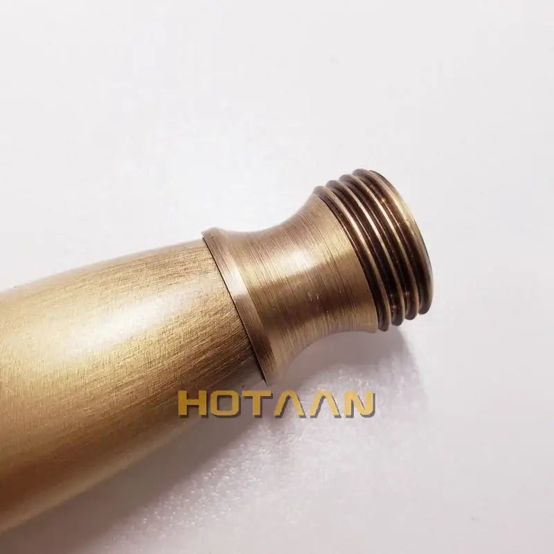 Antique brass handheld shower head with circular spray face and brushed finish metal surface with threaded end