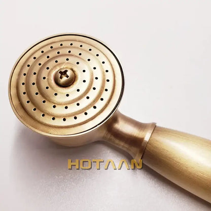 Antique brass handheld shower head with circular perforated face and wooden handle for bathroom use