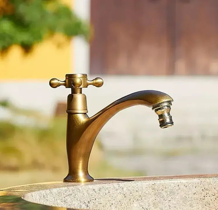 Antique brass single handle basin faucet with curved spout and cross-handle design for bathroom use