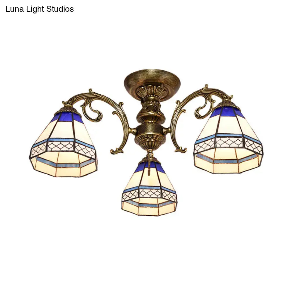 Antique brass-finished three-arm ceiling fixture with blue stained glass bell shades featuring geometric patterns