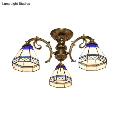 Antique brass-finished three-arm ceiling fixture with blue stained glass bell shades featuring geometric patterns