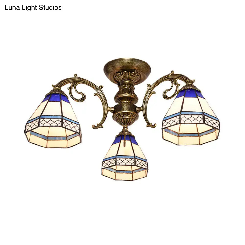 Antique brass-finished decorbites™ three-arm ceiling fixture with blue stained glass bell shades in geometric patterns