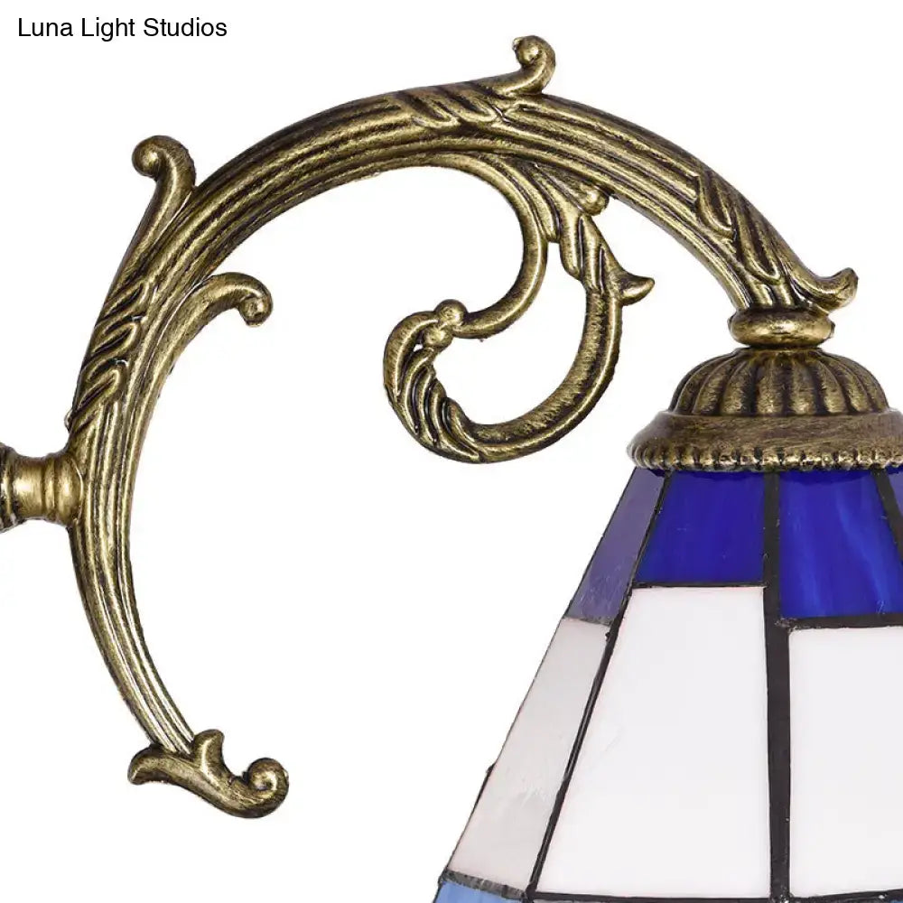 Antique brass-finished wall sconce with blue and white stained glass bell shade featuring geometric panels