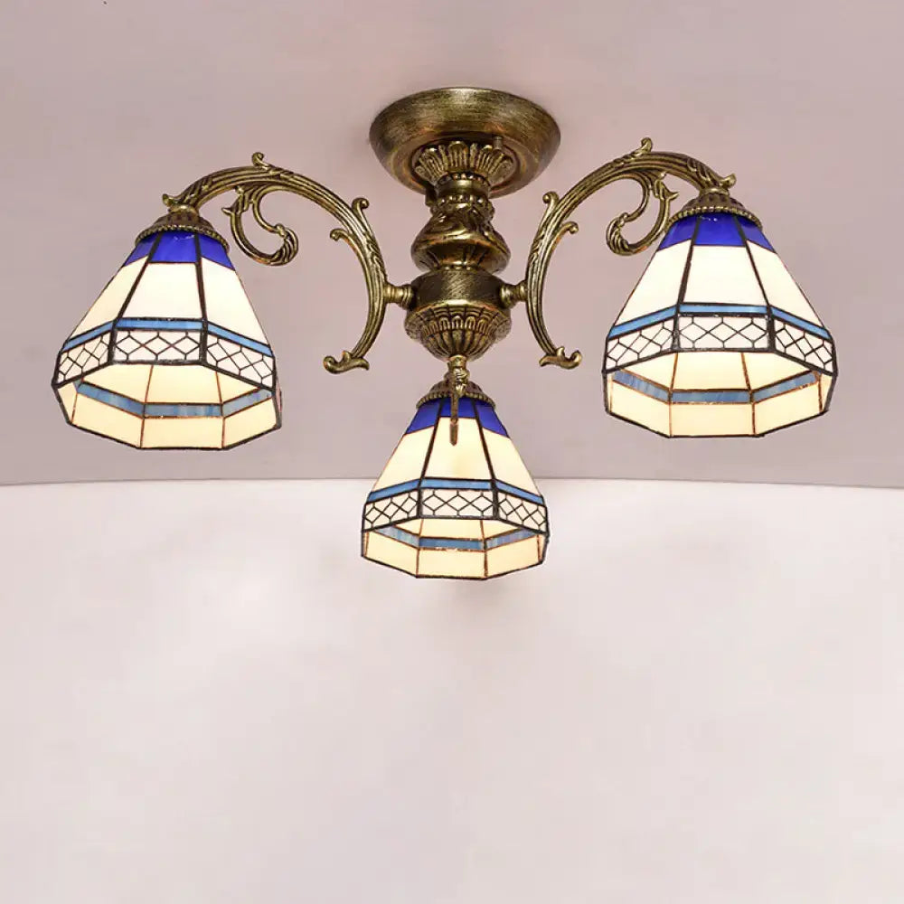 Antique brass three-arm semi flush mount ceiling fixture with blue and cream stained glass bell shades featuring geometric patterns