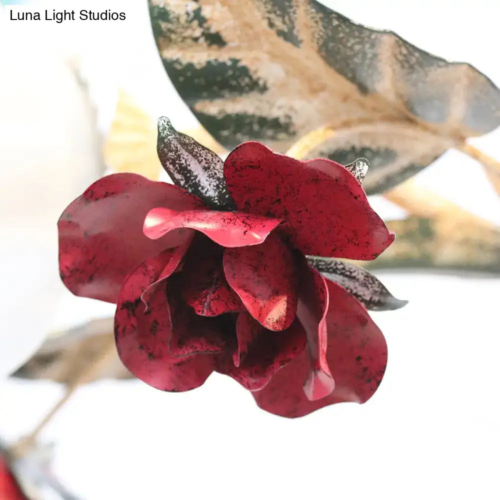 A handcrafted red metal rose with dark speckled petals and black leaves in a DecorBites™ living room ceiling chandelier