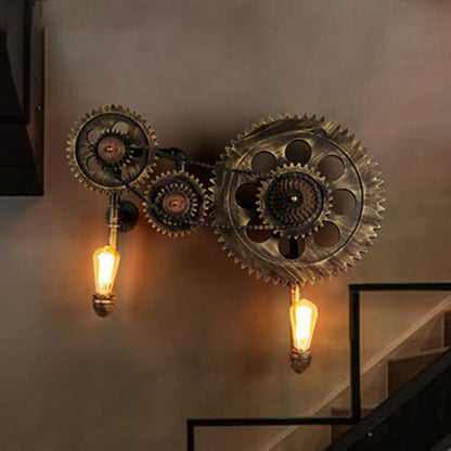 Aplique de pared industrial de dos luces con engranajes, en bronce antiguo.