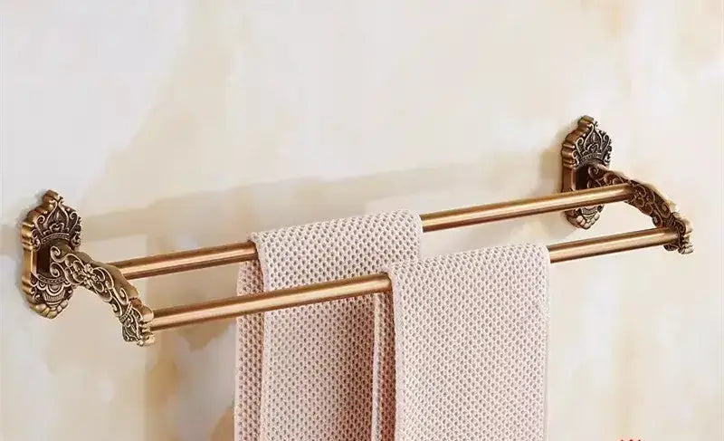 Antique brass double towel rack with ornate scrollwork ends holding beige towels in decorbites bronze carved bath set