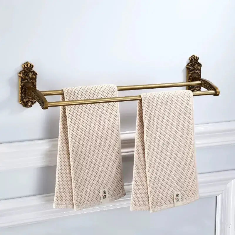 Beige textured towel with subtle dot pattern hanging on ornate decorbites bronze carved double-bar rack bath accessories set
