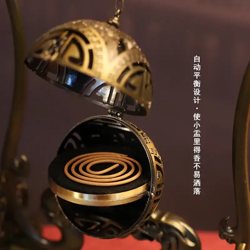 Golden intricately engraved spherical incense burner with black interior and coiled stick for living room zen decorbites dragon alloy