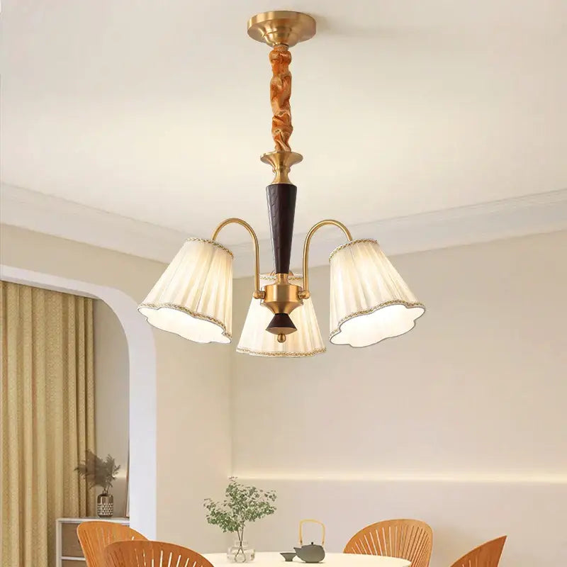 Antique copper chandelier with gold-toned twisted wooden stem and three cream pleated lampshades for dining room
