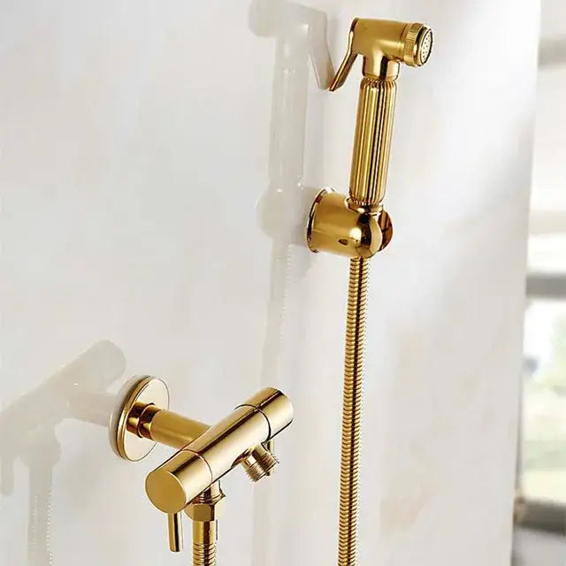 Gold-colored brass bidet shattaf with textured ribbed handle and flexible braided hose for hygienic bathroom use