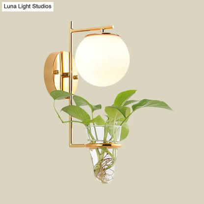 Aplique de pared antiguo dorado/negro con pantalla esférica y cristal crema/gris ahumado, lámpara de pared de una cabeza para dormitorio con maceta de cristal transparente.