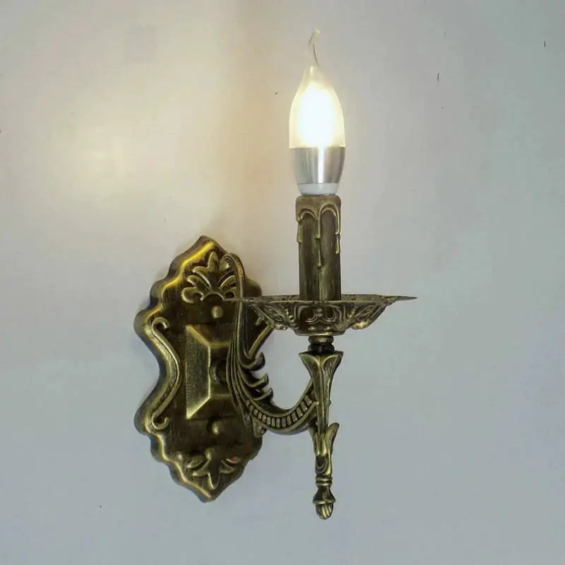 Antique gold brass retro european wall light with ornate scrollwork and single lit bulb for bedroom sconce lighting