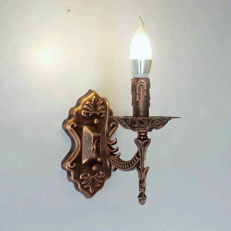 Antique gold retro european wall light with ornate bronze-finished candle-style sconce design glowing in bedroom