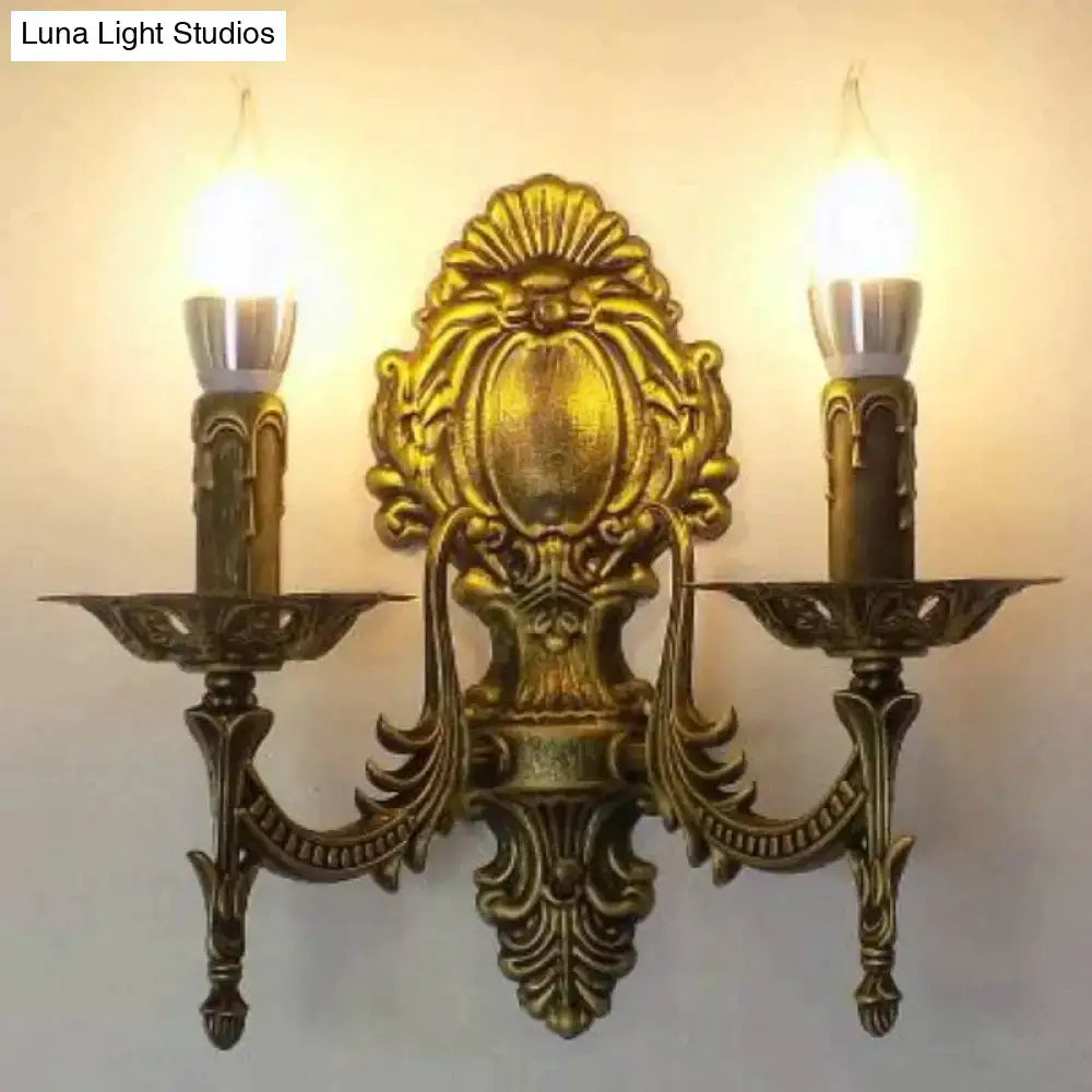 Antique gold retro european wall light with ornate symmetrical design and two candle-like bulbs for bedroom use