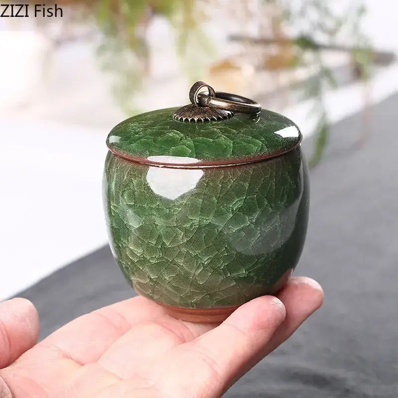 A small glossy green ceramic tea caddy with ice cracked texture glaze and ornate metallic lid for kitchen storage