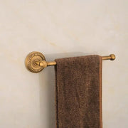 A plush brown towel hangs from an antique ornate decorbites brass round towel ring with decorative detailing