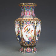 An ornate octagonal porcelain vase with vibrant hand-painted birds and flowers and gold trim from a porcelain vase collection