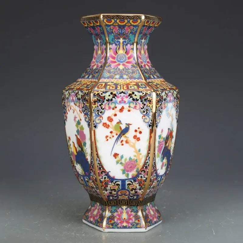 An ornate octagonal porcelain vase with vibrant hand-painted birds and flowers and gold trim from a porcelain vase collection