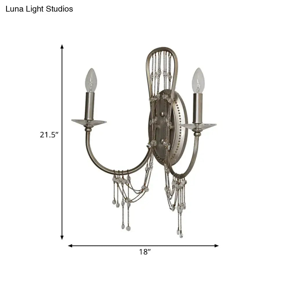 Antique silver crystal wall light sconce with curved arm featuring two lights and crystal bead chain accents for bedroom use