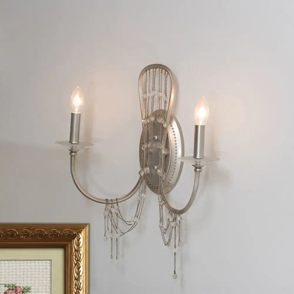 Antique silver crystal wall light sconce with two curved arms and ornate metalwork featuring crystal bead chains