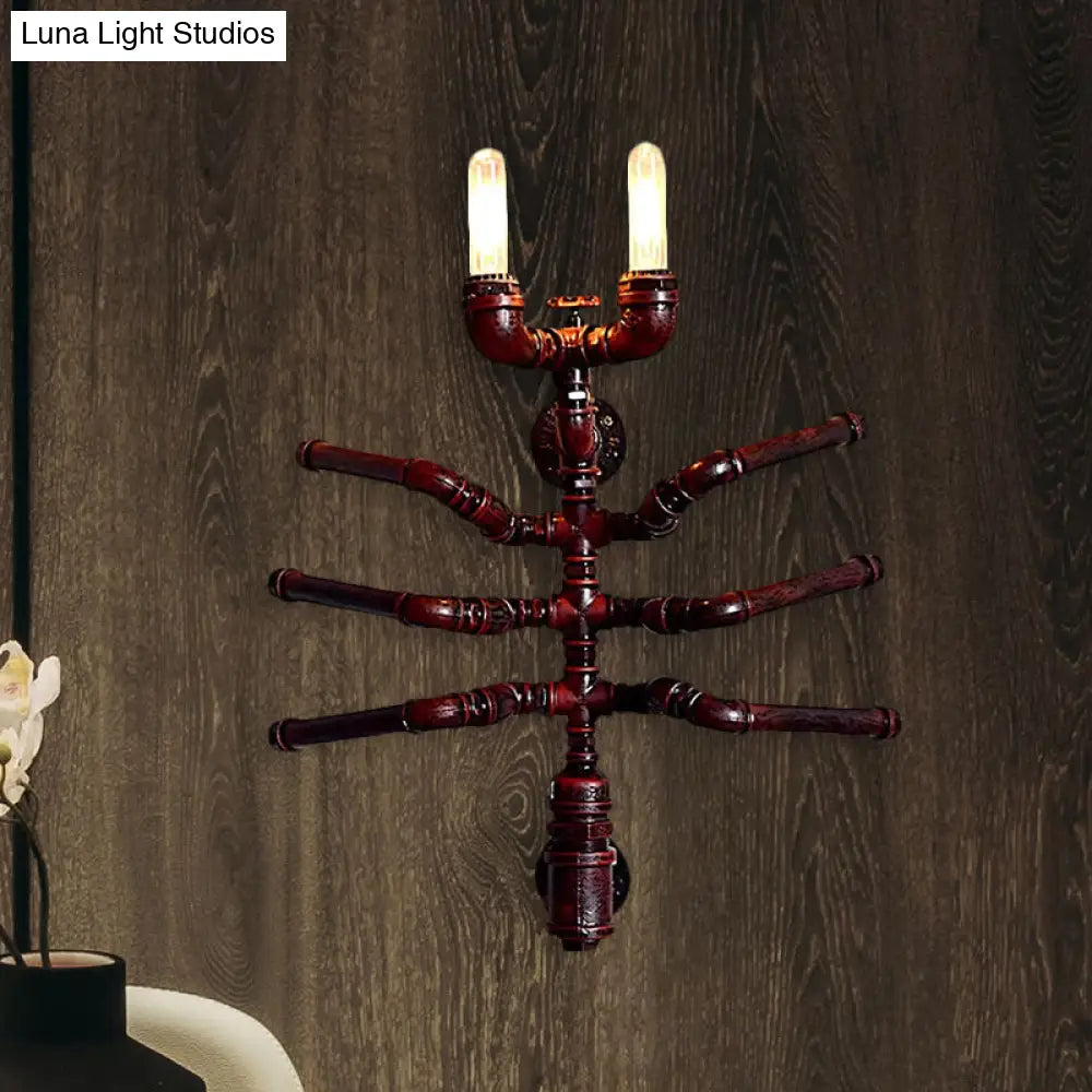 Aplique de pared estilo antiguo con forma de araña, dos bombillas y diseño rústico de tubería.