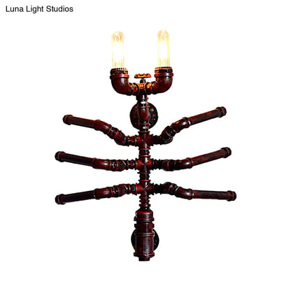 Aplique de pared estilo antiguo con forma de araña, dos bombillas y diseño rústico de tubería.