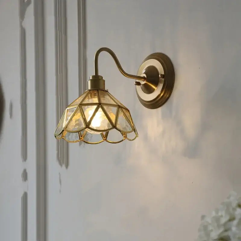 Antique brass wall light fixture with geometric faceted teal glass shade for bedroom sconce lighting