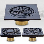 Black brass shower drain cover with intricate bird and flower carvings on a gold-toned metallic base decorbites black brass