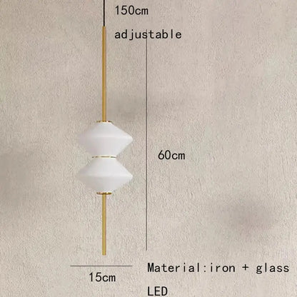 A modern art deco pendant light with two white faceted glass shades on a gold-toned iron rod for dining room