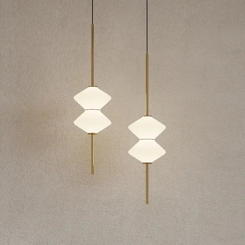 Two elegant art deco pendant lights with gold-toned rods and stacked white glass shades for dining room lighting