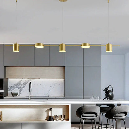 Art deco black and gold linear pendant light with cylindrical light sources suspended above kitchen island