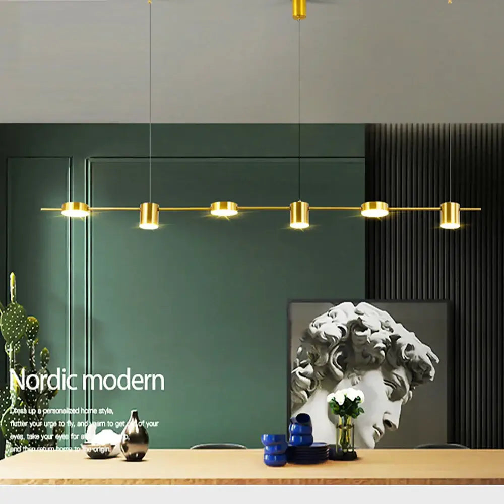 Gold-toned art deco linear pendant light with five cylindrical light sources suspended by thin cords for dining room