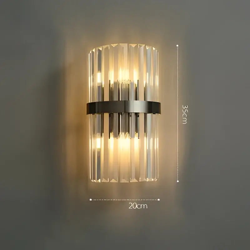 A modern art deco black and gold stainless wall sconce with ribbed glass and vertical crystal rods by decorbites emitting warm light