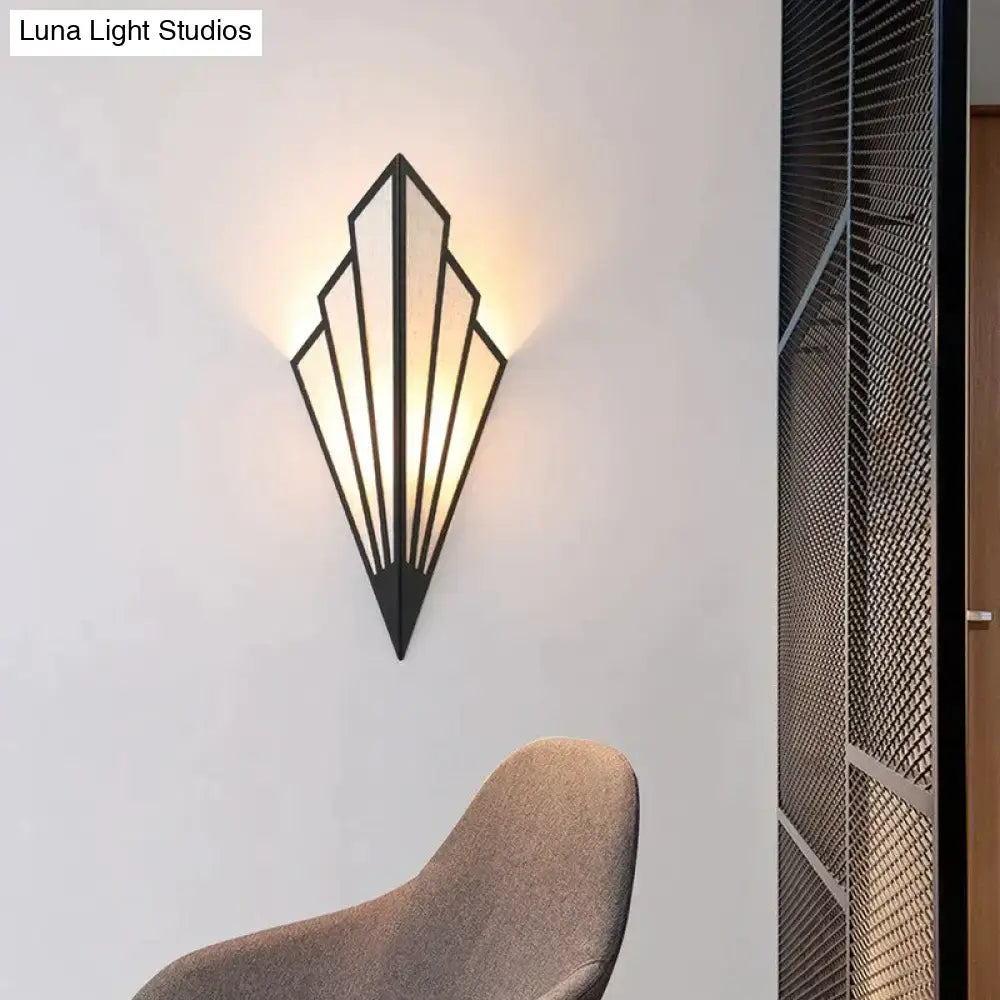 Black metal art deco wall light with geometric diamond shape modern fan design and warm glowing light for bedroom