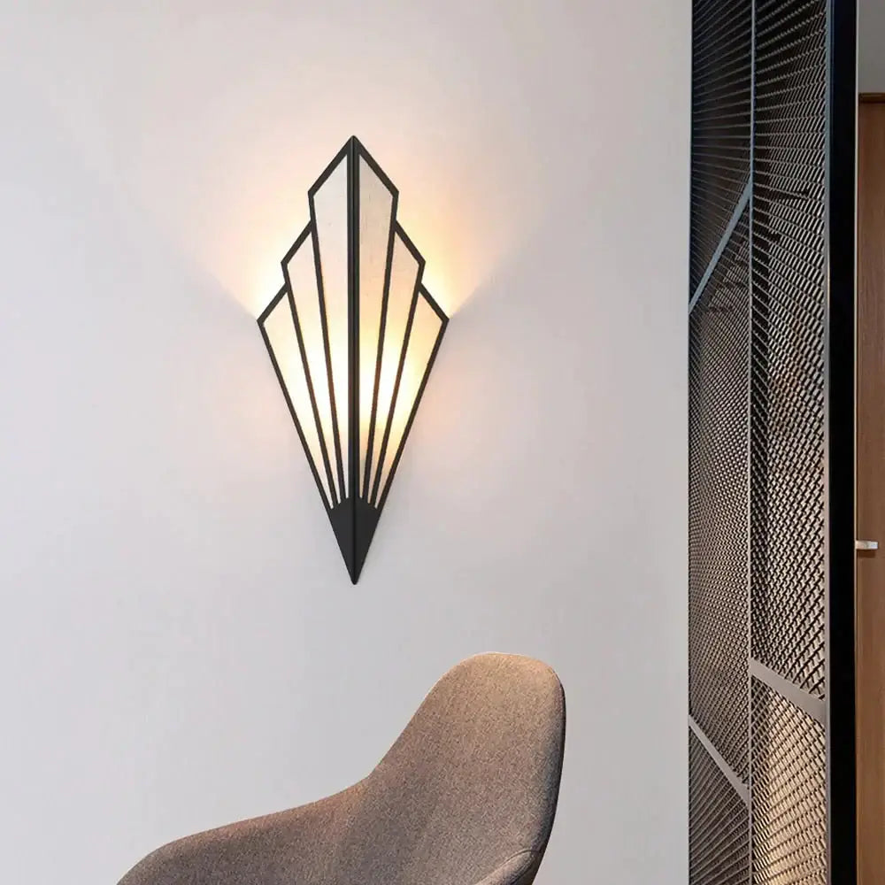 Black metal art deco wall light with a geometric diamond shape modern fan design and warm glowing light for bedroom
