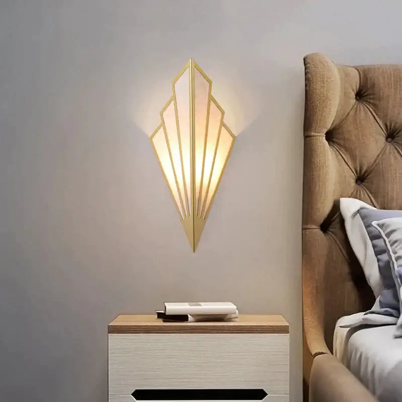 Art deco gold-toned wall light with diamond shape modern geometric fan design and frosted glass panels for bedroom use