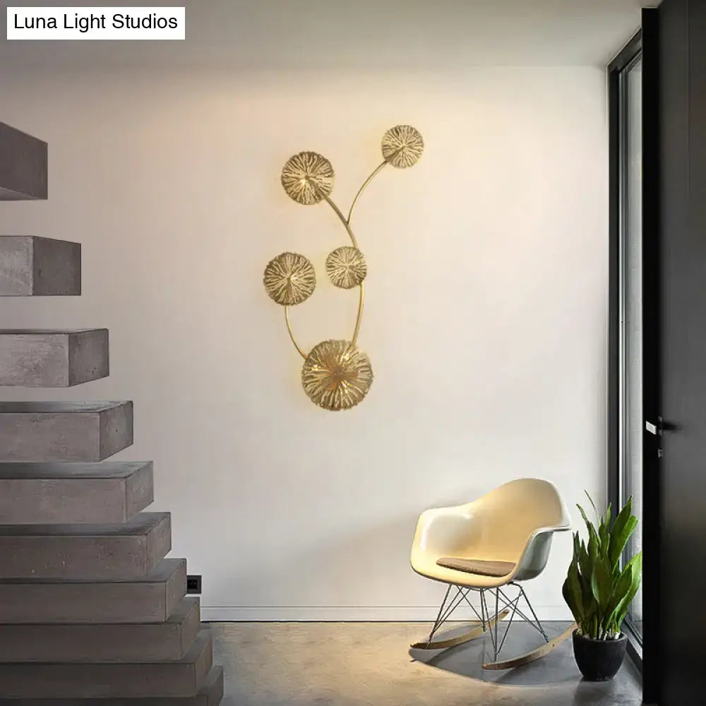 Gold-toned metal art deco wall mount light fixture featuring five sunburst discs on a curved branch for bedroom use