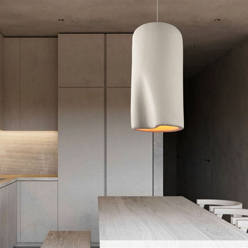 White cylindrical pendant light with orange interior, modern design.