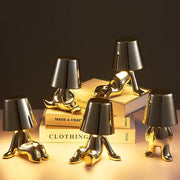 Articulated golden man table lamp with glossy finish and black lampshade head serving as a bedroom night light
